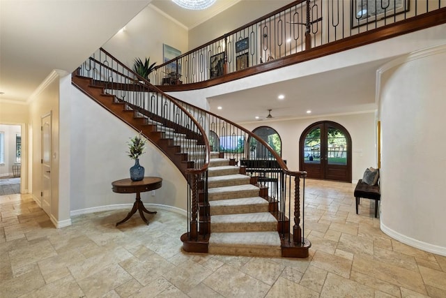 stairs featuring crown molding, a high ceiling, french doors, stone tile floors, and baseboards