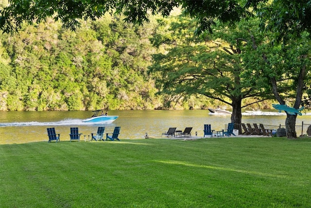 view of community with a lawn, a water view, and a forest view
