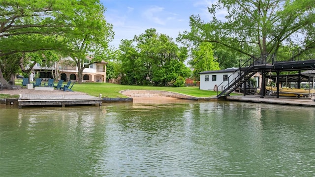 dock area featuring a yard, a water view, and stairs