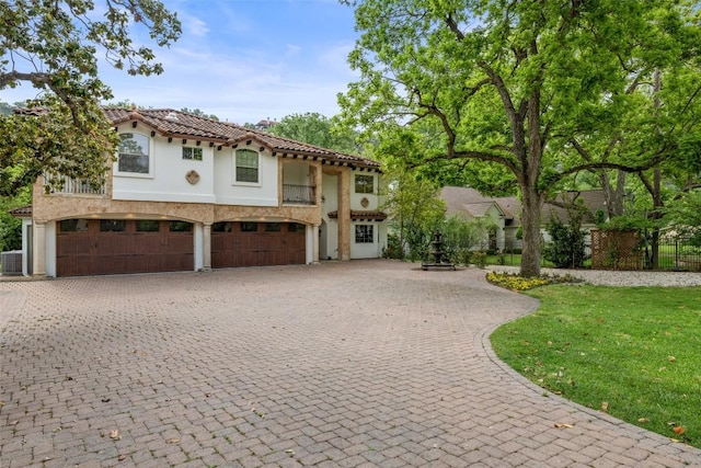 mediterranean / spanish-style home with a tile roof, a garage, stucco siding, a balcony, and curved driveway