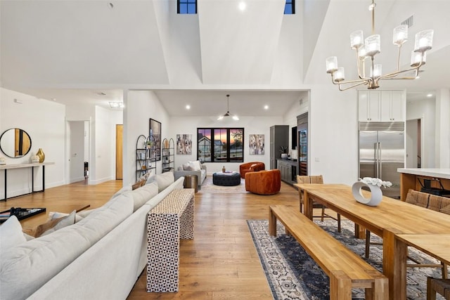 living room with an inviting chandelier, light wood finished floors, high vaulted ceiling, recessed lighting, and visible vents