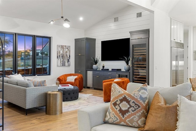living room with wood walls, visible vents, light wood finished floors, and wine cooler
