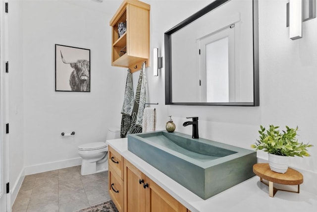 bathroom with toilet, baseboards, tile patterned floors, and vanity