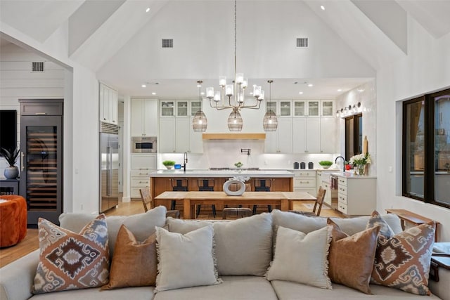 living room featuring a notable chandelier, high vaulted ceiling, visible vents, and wine cooler