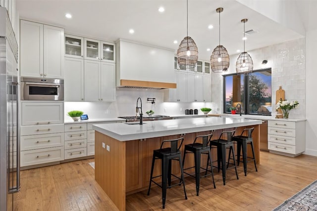kitchen with light wood-type flooring, light countertops, custom exhaust hood, and white cabinets
