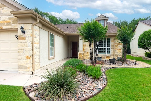 doorway to property with a yard, an attached garage, a shingled roof, and stone siding