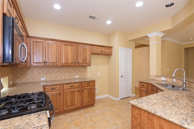 kitchen featuring black microwave, a sink, brown cabinetry, visible vents, and range with gas cooktop