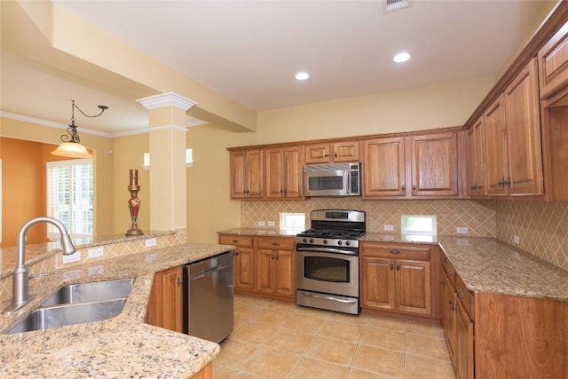 kitchen featuring a sink, appliances with stainless steel finishes, brown cabinetry, and decorative columns