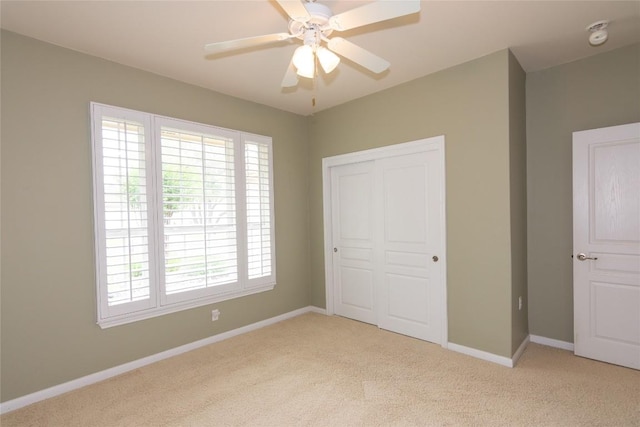 unfurnished bedroom featuring baseboards, multiple windows, light carpet, and a closet