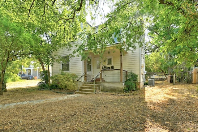 view of front of house featuring a porch, central AC, and fence