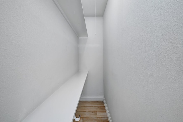 walk in closet featuring attic access and wood finished floors