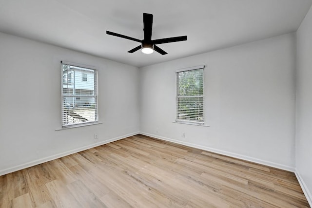empty room with plenty of natural light, a ceiling fan, baseboards, and wood finished floors