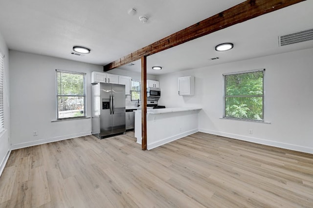 unfurnished living room with light wood-style floors, baseboards, beam ceiling, and visible vents