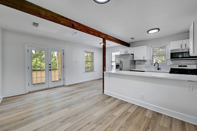 kitchen featuring light countertops, baseboards, a sink, light wood finished floors, and stainless steel appliances