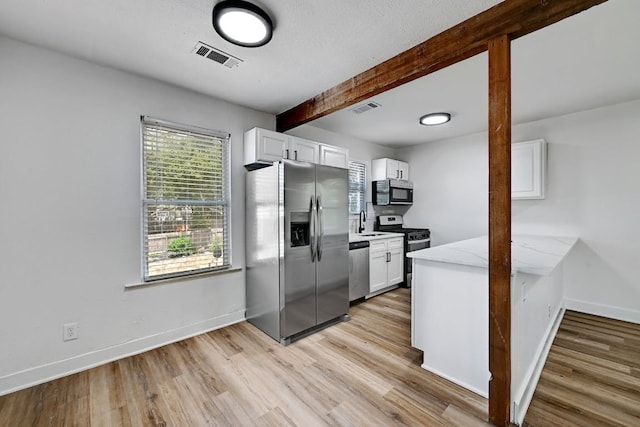 kitchen with visible vents, beam ceiling, baseboards, white cabinets, and stainless steel appliances