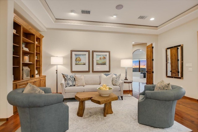 living room featuring crown molding, a tray ceiling, and visible vents