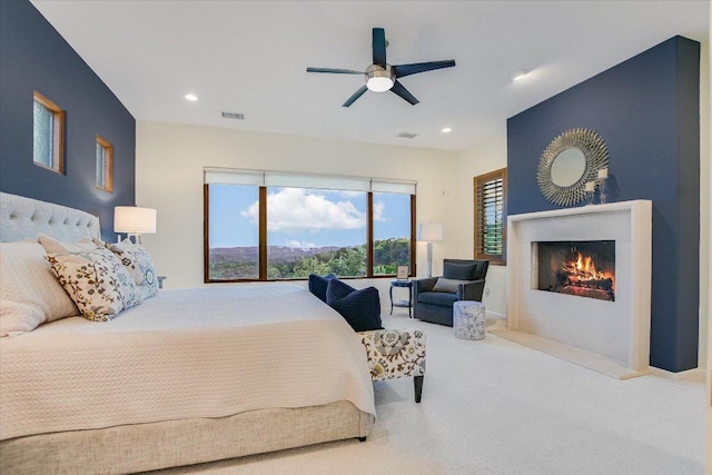 carpeted bedroom featuring visible vents, recessed lighting, a ceiling fan, and a warm lit fireplace