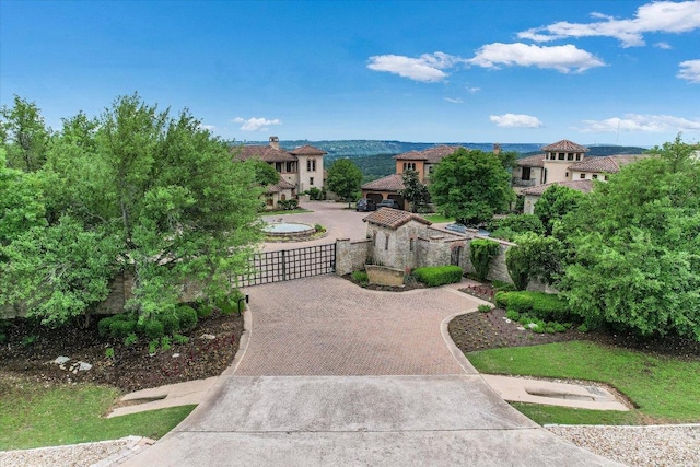 view of property's community with curved driveway, a gate, and fence