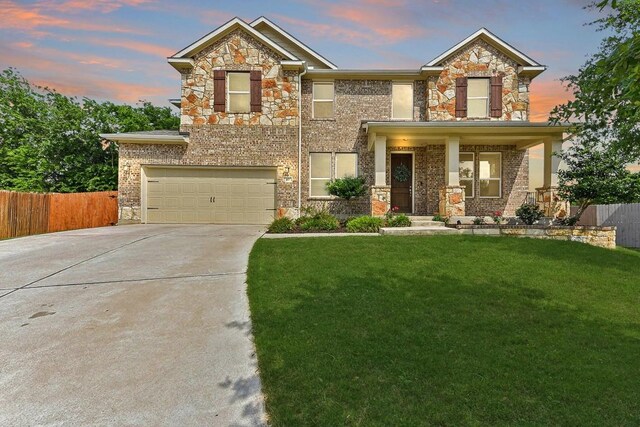 craftsman inspired home featuring a yard, a garage, fence, concrete driveway, and stone siding