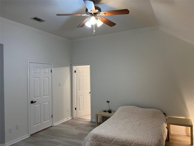 bedroom featuring visible vents, crown molding, wood finished floors, baseboards, and a ceiling fan