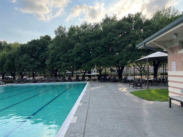 community pool with a patio and fence