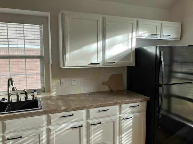 1728 Dapplegrey Ln, Austin, TX 78727 - kitchen featuring freestanding refrigerator, backsplash, and white cabinetry