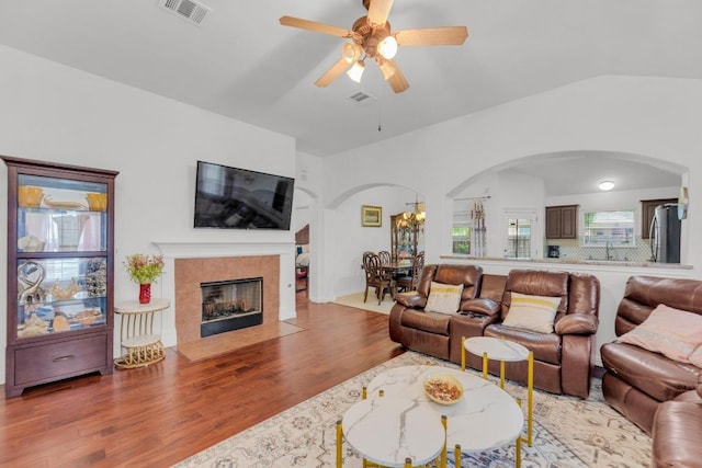 living room with arched walkways, a ceiling fan, visible vents, and wood finished floors