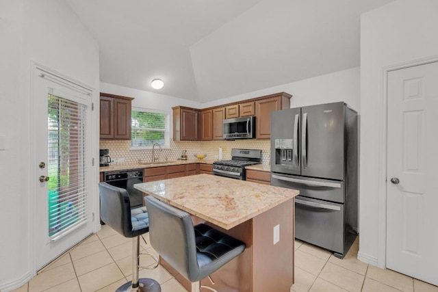 kitchen featuring decorative backsplash, lofted ceiling, a sink, appliances with stainless steel finishes, and light tile patterned floors