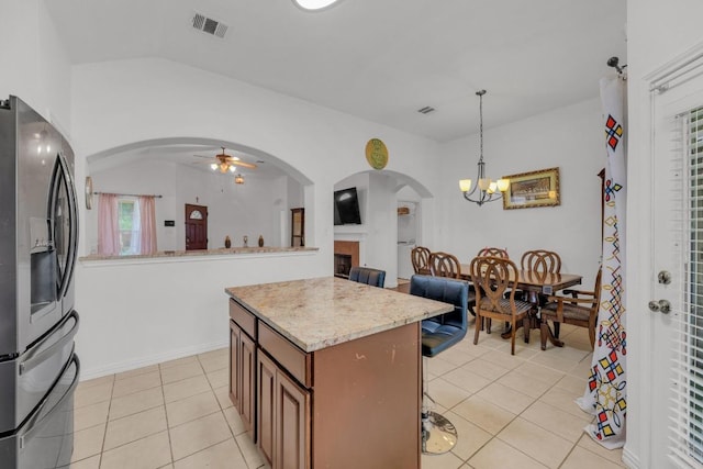 kitchen with arched walkways, ceiling fan with notable chandelier, light tile patterned floors, stainless steel refrigerator with ice dispenser, and visible vents