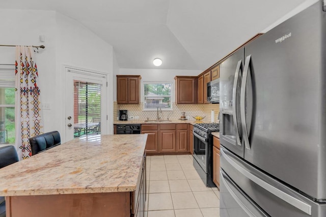 kitchen featuring lofted ceiling, light countertops, a sink, appliances with stainless steel finishes, and light tile patterned floors