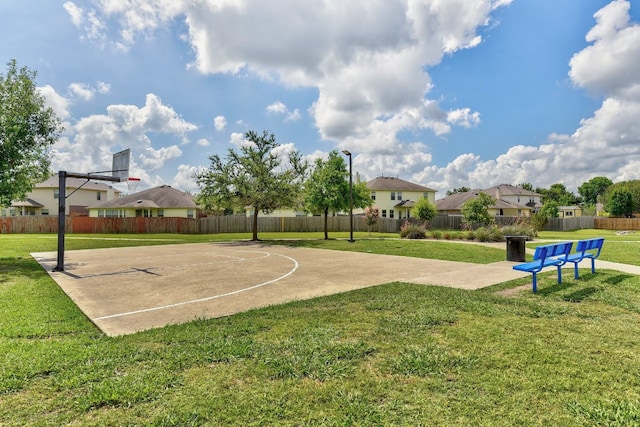 view of sport court with a lawn, fence, a residential view, and basketball hoop