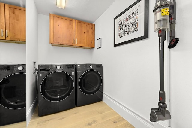 washroom with independent washer and dryer, baseboards, light wood-type flooring, and cabinet space