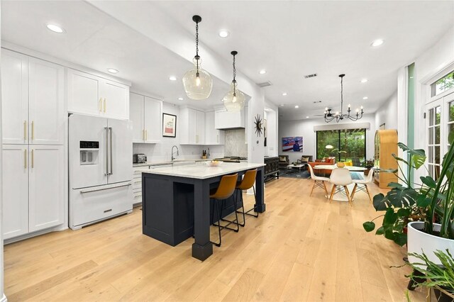 705 W Johanna St Unit B, Austin, TX 78704 - kitchen with high end white fridge, light wood-style flooring, white cabinetry, a chandelier, and recessed lighting