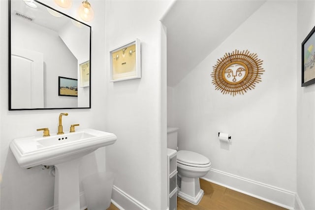 bathroom with baseboards, wood finished floors, visible vents, and toilet