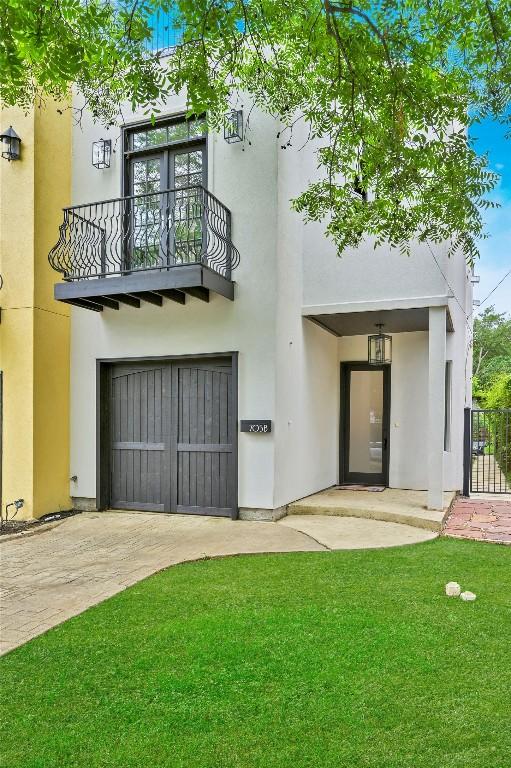 back of house with a garage, stucco siding, a yard, and a balcony