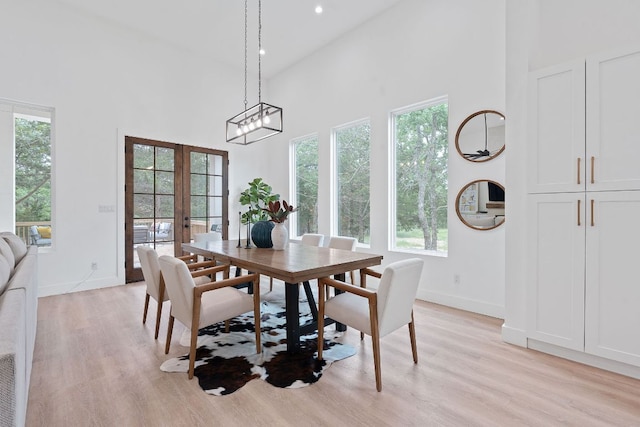 dining area with light wood-style floors, a high ceiling, and a healthy amount of sunlight