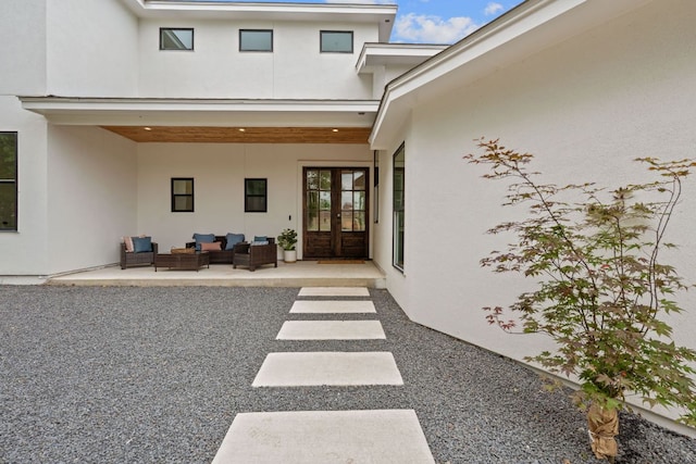 rear view of property featuring french doors, stucco siding, an outdoor living space, and a patio area