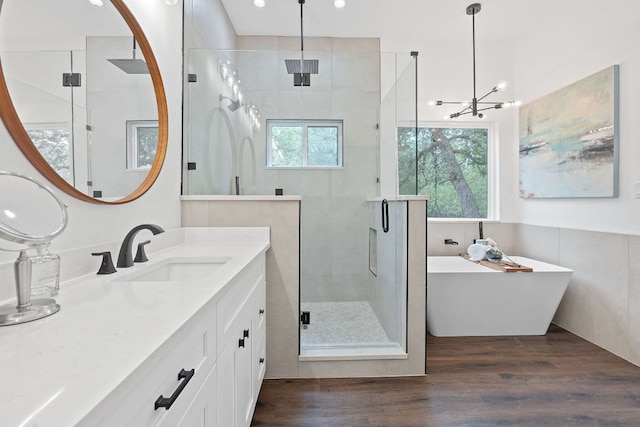 full bath with a stall shower, wood finished floors, vanity, a notable chandelier, and recessed lighting
