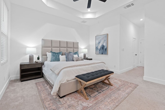 bedroom with a tray ceiling, visible vents, baseboards, and carpet