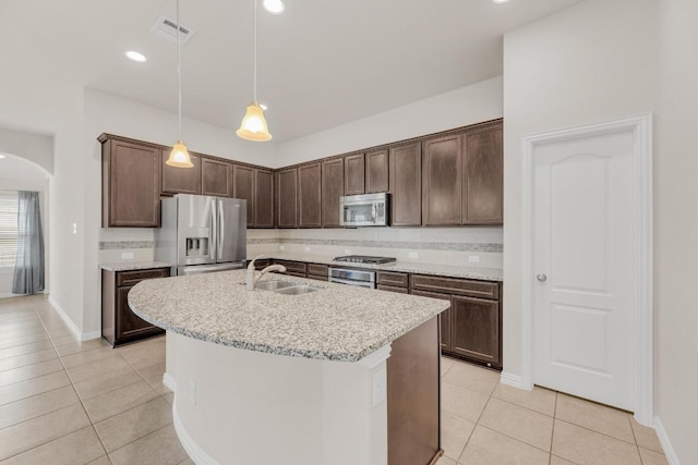 kitchen featuring light tile patterned flooring, appliances with stainless steel finishes, a sink, arched walkways, and visible vents