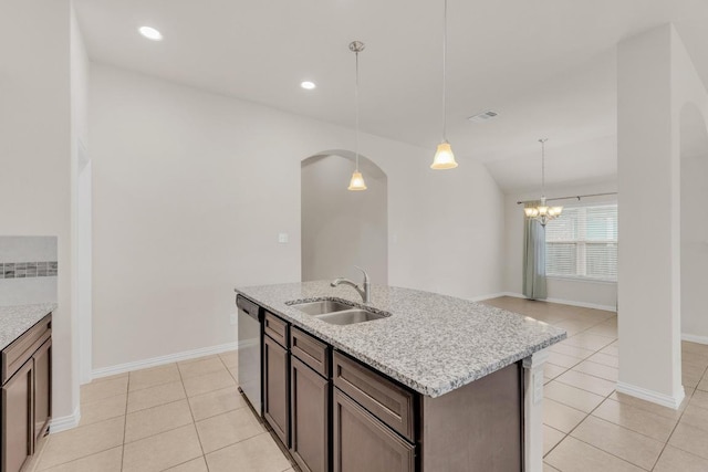 kitchen featuring stainless steel dishwasher, pendant lighting, arched walkways, a sink, and light tile patterned floors