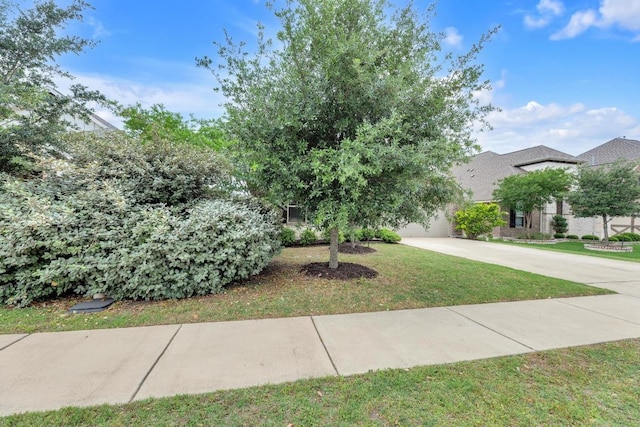 view of front of property featuring a garage, concrete driveway, and a front yard