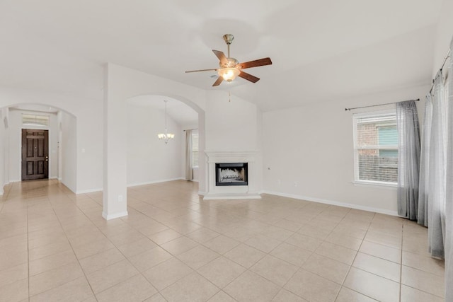 unfurnished living room featuring light tile patterned floors, arched walkways, ceiling fan with notable chandelier, and lofted ceiling