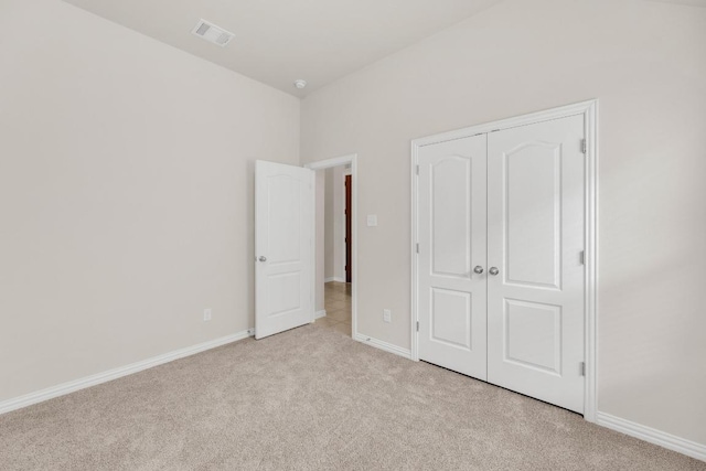 unfurnished bedroom with light colored carpet, baseboards, visible vents, and a closet