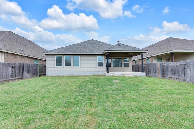 rear view of property featuring a fenced backyard, a lawn, and roof with shingles