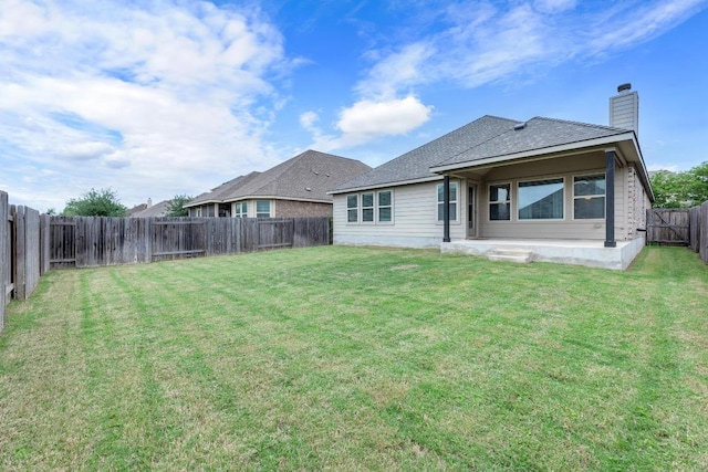 back of house featuring a fenced backyard, roof with shingles, a chimney, a patio area, and a yard