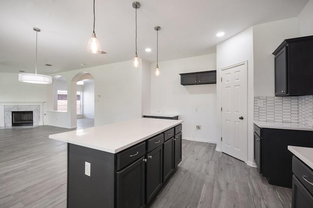 18816 Sandy Shore Dr, Pflugerville, TX 78660 - kitchen featuring decorative backsplash, a kitchen island, arched walkways, light countertops, and light wood-style floors