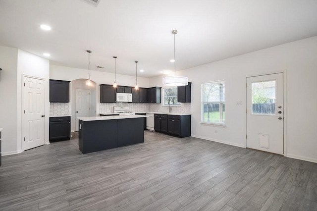 18816 Sandy Shore Dr, Pflugerville, TX 78660 - kitchen featuring stove, a center island, wood finished floors, white microwave, and backsplash
