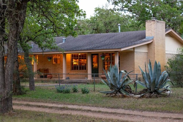 ranch-style home with brick siding, a shingled roof, and a chimney