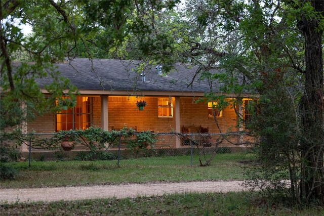 view of front of property with fence private yard, roof with shingles, and brick siding